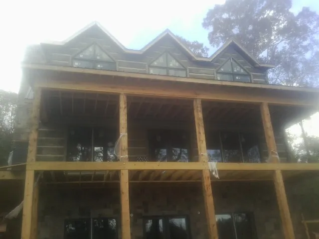 Dormers and porch framing on a large log home under construction — Roof Coating work by our crew in Greenwich