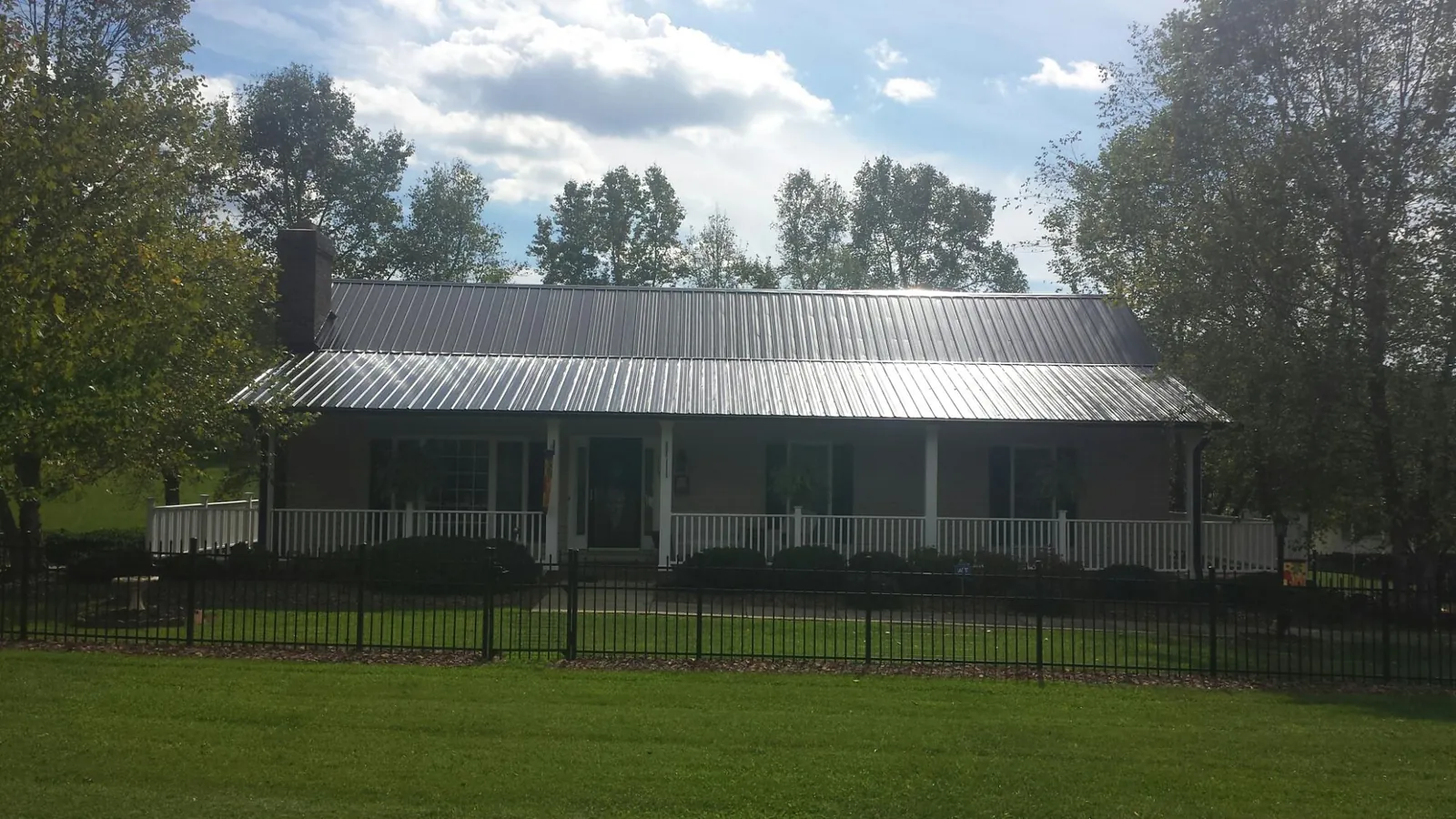 Gray metal roof on a brick ranch with a full width front porch — Gutter Guard Installation work by our crew in Greenwich